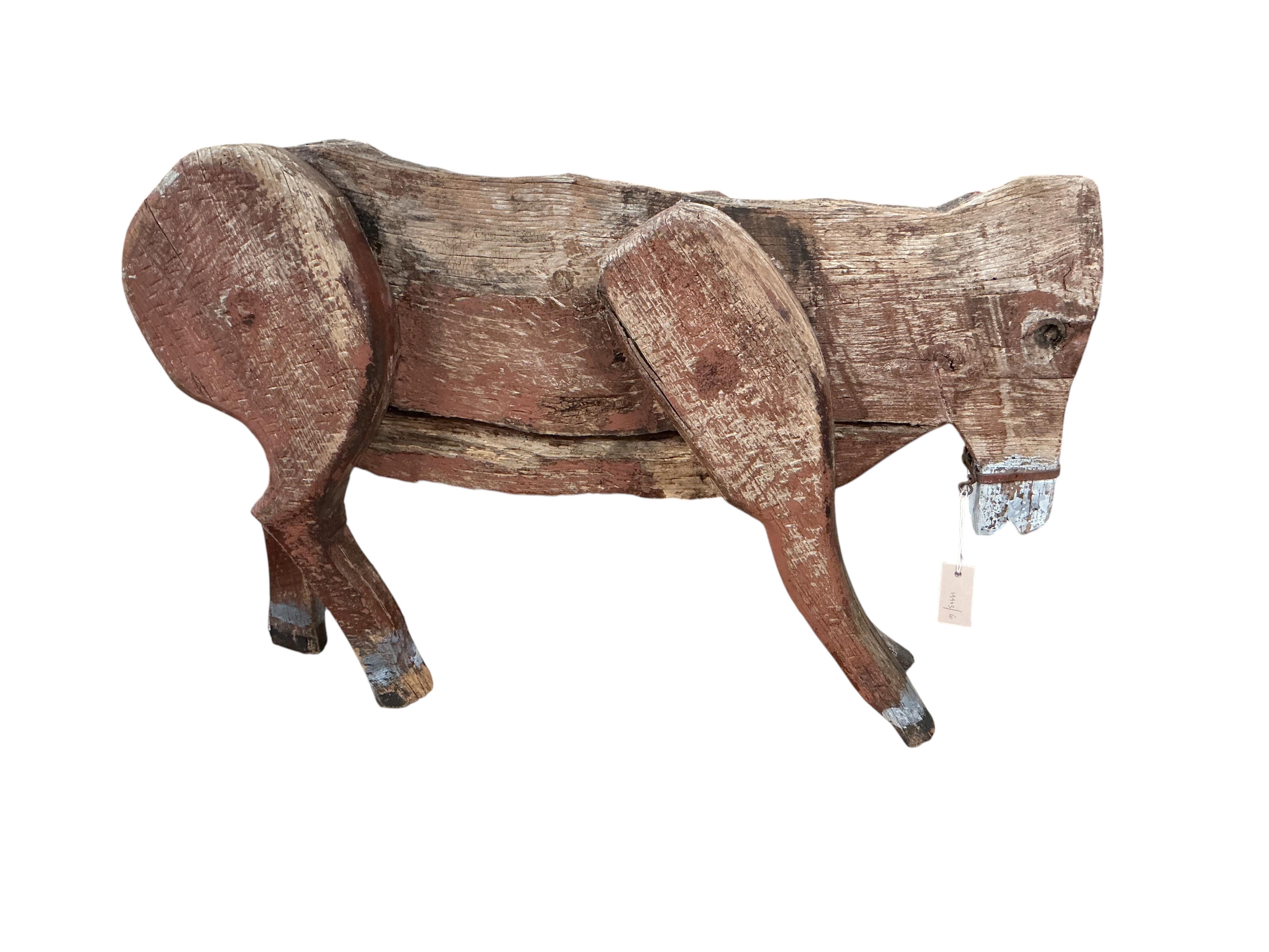 A 19th century primitive painted wood model of a cow with articulated limbs, length 100cm, height 62cm